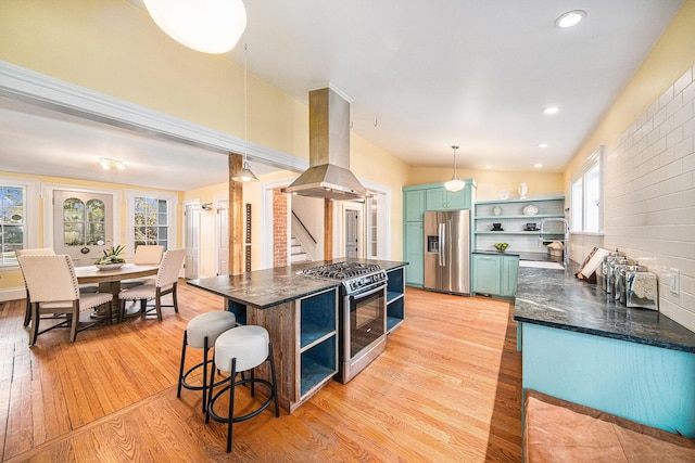 kitchen with island range hood, light wood-style floors, appliances with stainless steel finishes, open shelves, and ornate columns