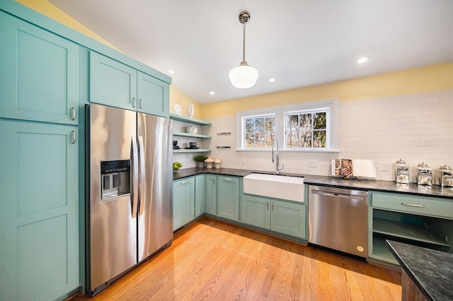 kitchen with a sink, appliances with stainless steel finishes, open shelves, light wood finished floors, and tasteful backsplash