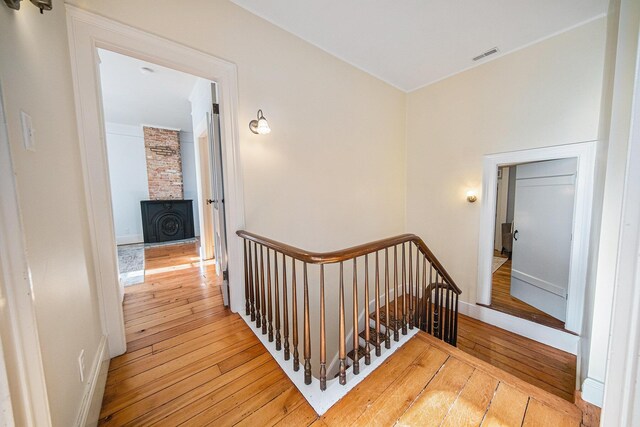 stairway with baseboards, a fireplace, visible vents, and hardwood / wood-style floors