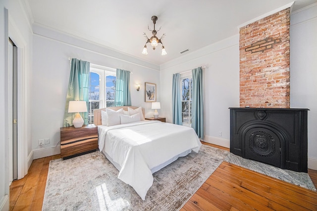 bedroom with a chandelier, visible vents, baseboards, light wood-style floors, and ornamental molding