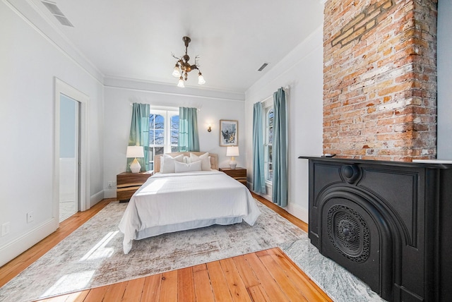 bedroom with visible vents, crown molding, baseboards, and wood finished floors