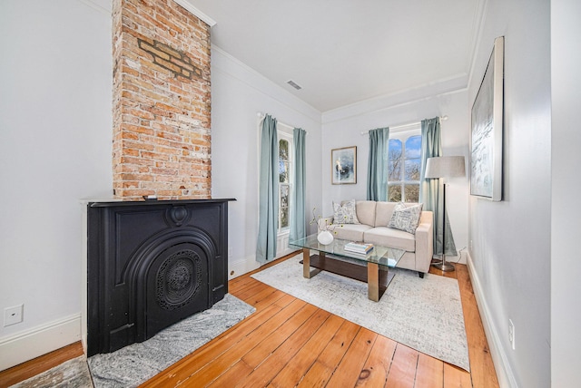 living area with wood-type flooring, visible vents, crown molding, and baseboards