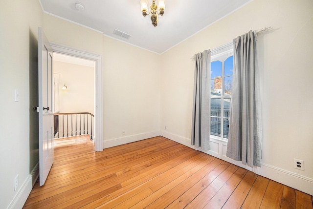 spare room featuring light wood-style floors, baseboards, visible vents, and crown molding