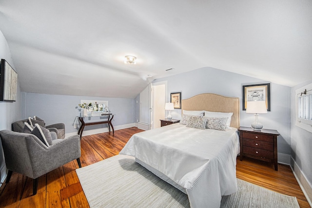 bedroom with lofted ceiling, baseboards, and hardwood / wood-style floors