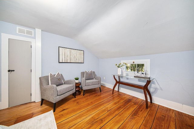 sitting room with vaulted ceiling, light wood-style flooring, and visible vents