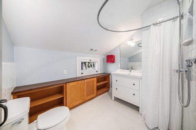 bathroom with lofted ceiling, visible vents, toilet, vanity, and tiled shower