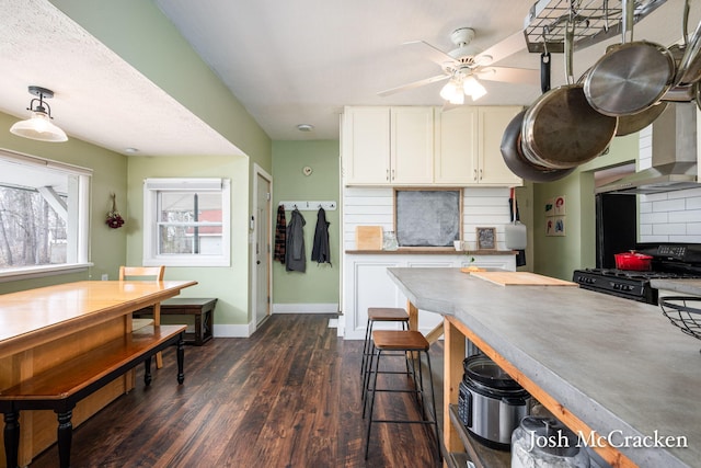 kitchen featuring tasteful backsplash, black range with gas cooktop, baseboards, white cabinets, and dark wood-style flooring