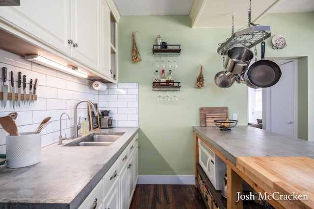 kitchen with dark wood-style floors, white cabinetry, decorative backsplash, and a sink