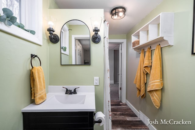 bathroom with wood finished floors, vanity, and baseboards