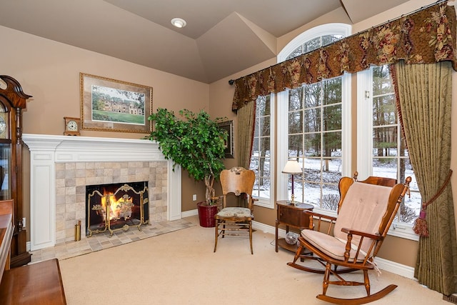 living area with lofted ceiling, carpet floors, a tiled fireplace, and baseboards