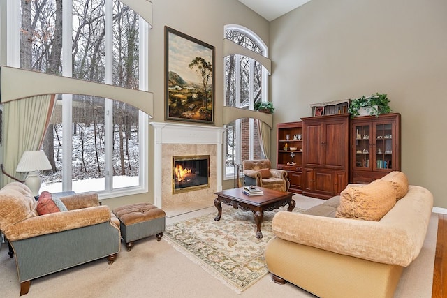 sitting room with carpet flooring, plenty of natural light, a high ceiling, and a premium fireplace