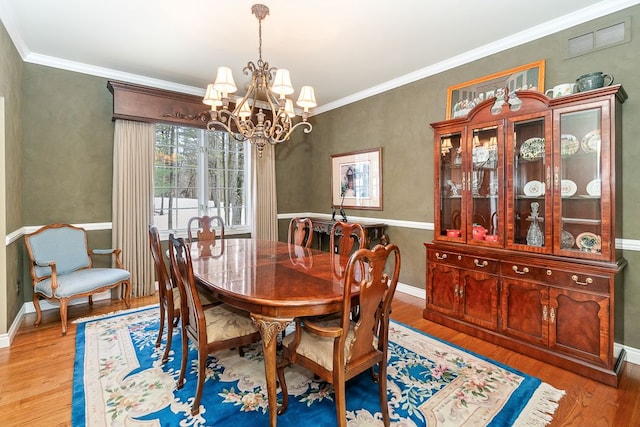 dining area featuring light wood finished floors, visible vents, crown molding, and an inviting chandelier