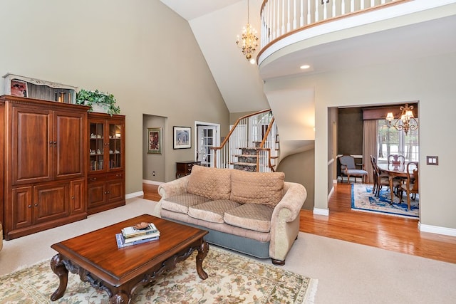 living room featuring a chandelier, high vaulted ceiling, baseboards, light wood-style floors, and stairway