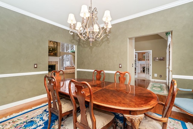 dining space featuring ornamental molding, wood finished floors, a tile fireplace, and baseboards