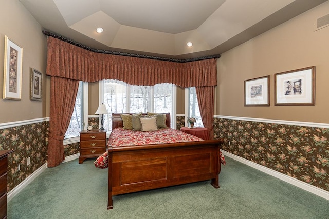 carpeted bedroom with wallpapered walls, baseboards, visible vents, wainscoting, and a tray ceiling