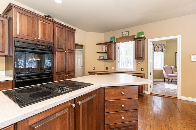 kitchen featuring dark wood finished floors, open shelves, light countertops, black appliances, and baseboards