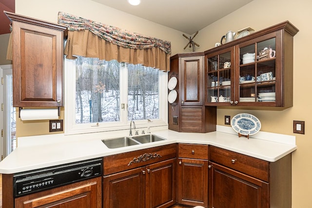 kitchen with glass insert cabinets, light countertops, a sink, and dishwasher