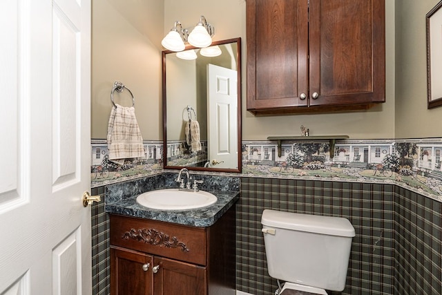 bathroom with a wainscoted wall, vanity, and toilet