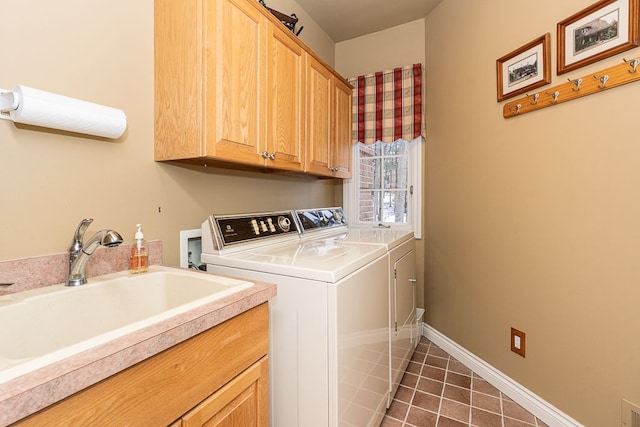 laundry room featuring cabinet space, baseboards, washer and clothes dryer, dark tile patterned floors, and a sink