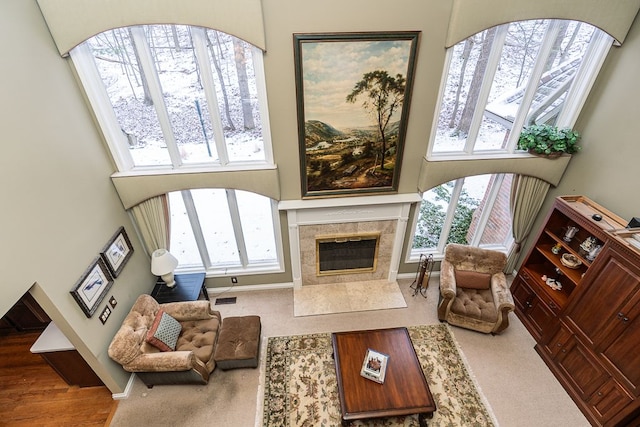 carpeted living room with a wealth of natural light, visible vents, a towering ceiling, and a tiled fireplace