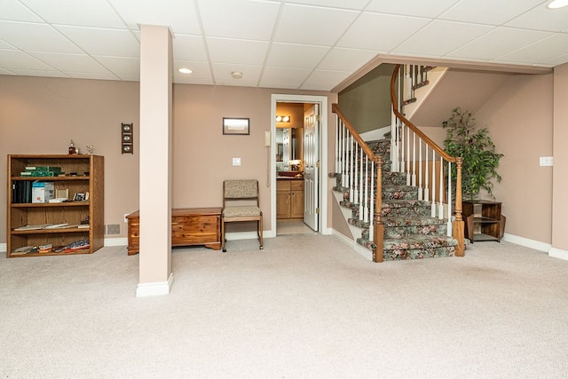 interior space featuring carpet, a drop ceiling, stairway, and baseboards