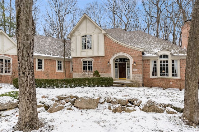 english style home with a shingled roof and brick siding