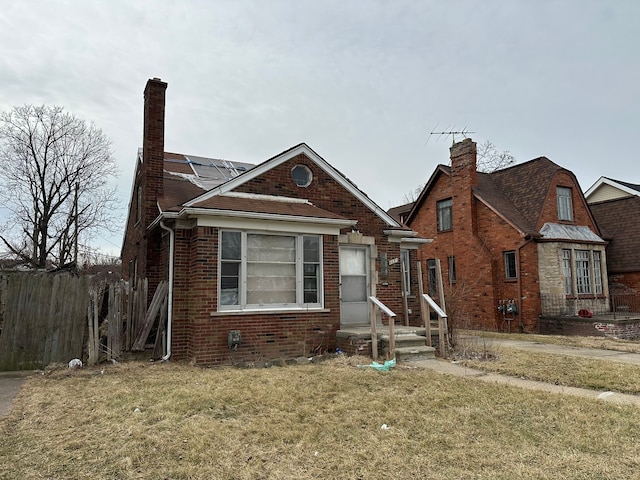 view of front facade with a front yard, solar panels, and brick siding