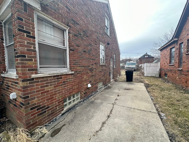 view of property exterior with brick siding and fence