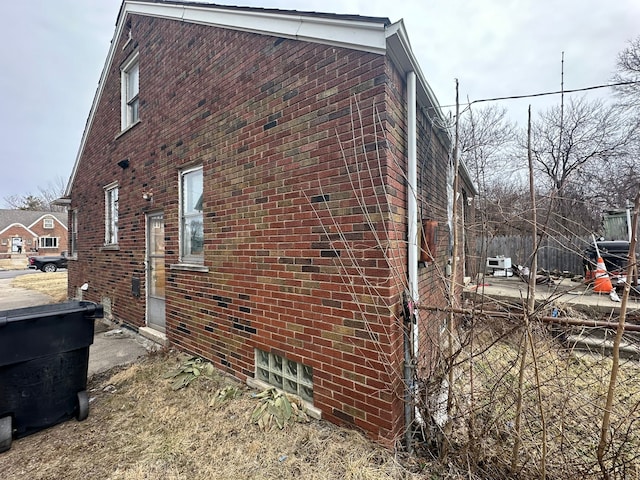 view of side of home featuring fence and brick siding