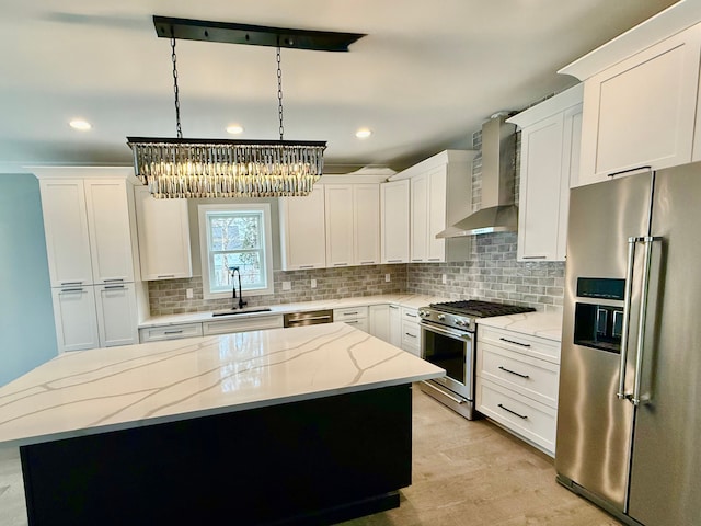 kitchen featuring wall chimney exhaust hood, a sink, a notable chandelier, a kitchen island, and high quality appliances