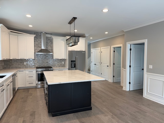 kitchen featuring backsplash, ornamental molding, a kitchen island, wall chimney exhaust hood, and appliances with stainless steel finishes