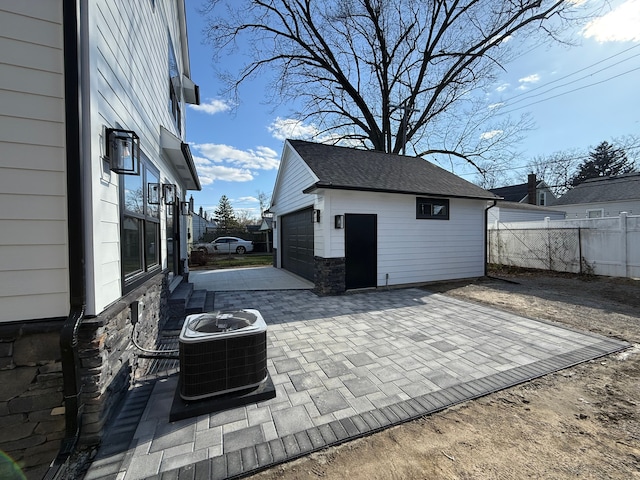 view of patio with an outdoor structure, fence, cooling unit, and a garage