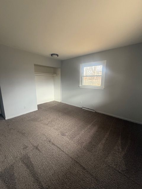 unfurnished room featuring dark colored carpet and visible vents