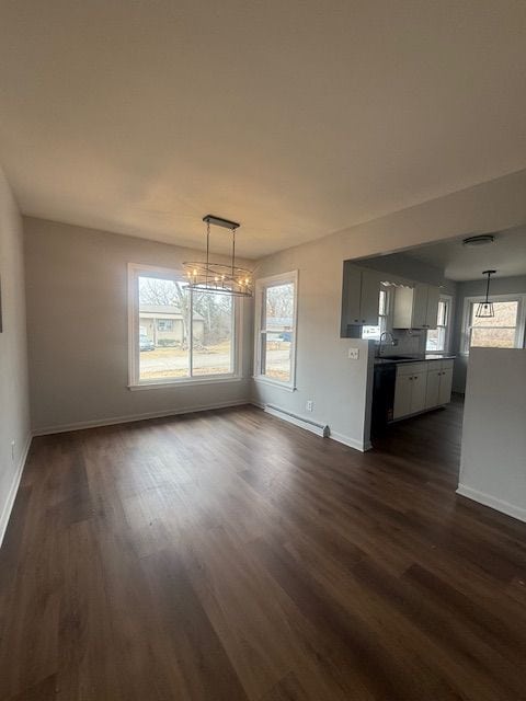 unfurnished dining area featuring a baseboard radiator, a sink, dark wood finished floors, and a healthy amount of sunlight