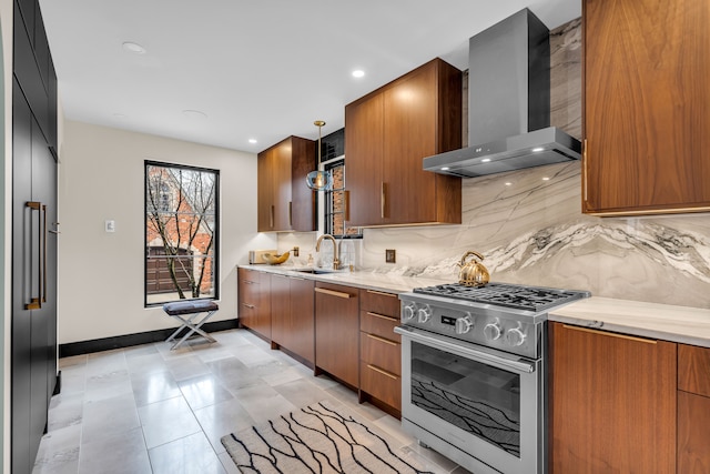 kitchen with wall chimney range hood, stainless steel gas range oven, decorative backsplash, and a sink