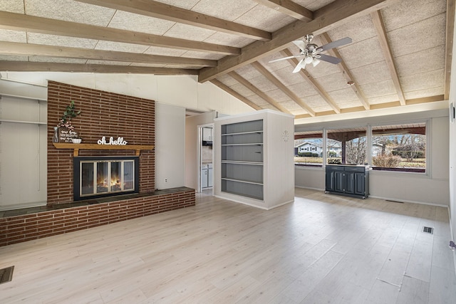 unfurnished living room featuring lofted ceiling with beams, a brick fireplace, visible vents, and wood finished floors