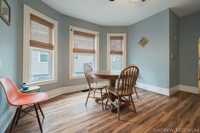 dining space featuring a ceiling fan, visible vents, baseboards, and wood finished floors