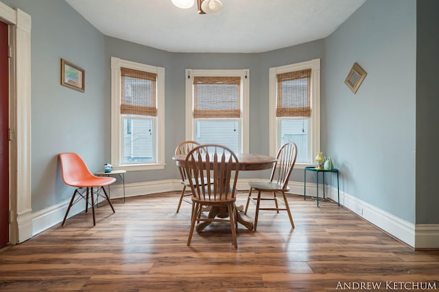 dining space with baseboards and wood finished floors