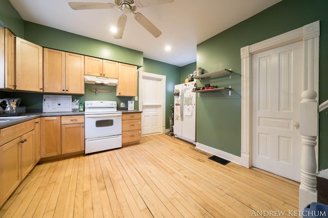 kitchen with light wood-style flooring, under cabinet range hood, white appliances, a sink, and dark countertops