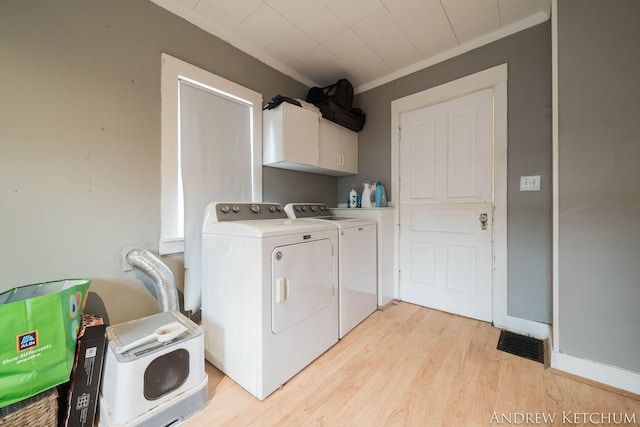 clothes washing area with cabinet space, baseboards, crown molding, light wood-type flooring, and washing machine and dryer