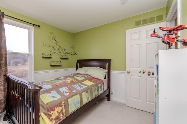 bedroom featuring carpet floors, a wainscoted wall, and visible vents