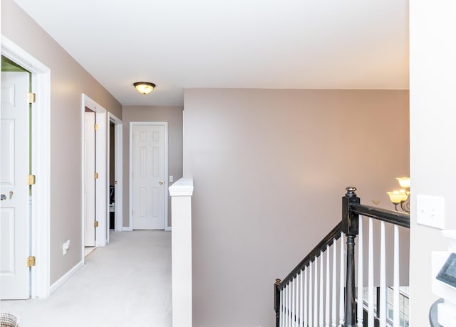 corridor with light carpet, an upstairs landing, and baseboards