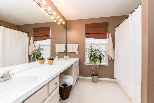 full bath with a sink, baseboards, and double vanity