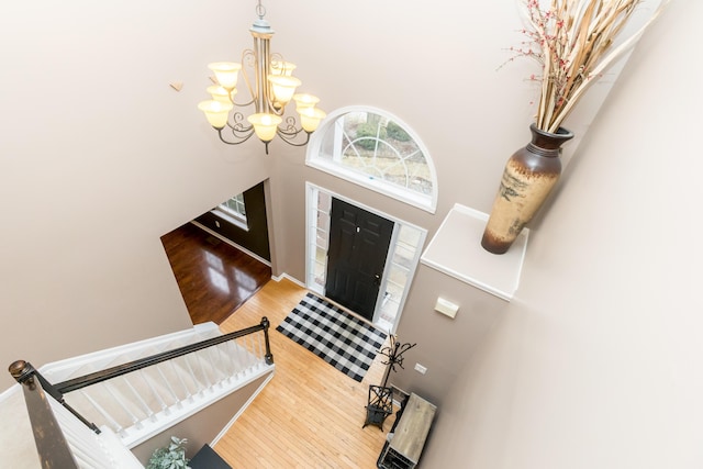 entryway featuring a notable chandelier, wood finished floors, a towering ceiling, baseboards, and stairs