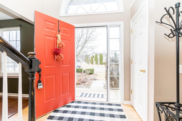 foyer with plenty of natural light, stairway, and light wood finished floors