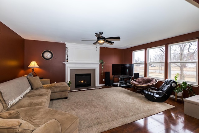 living area with a ceiling fan, a tile fireplace, and wood finished floors