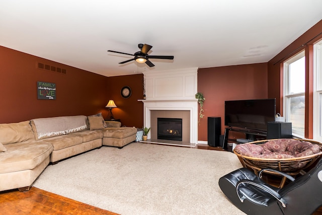 living area featuring ceiling fan, visible vents, wood finished floors, and a tile fireplace