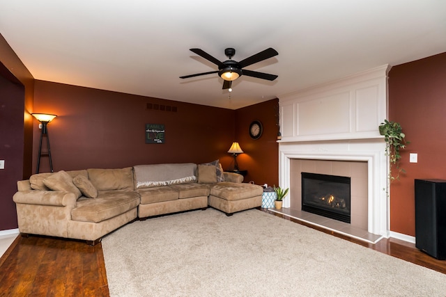 living room with a ceiling fan, a fireplace, visible vents, and dark wood-type flooring