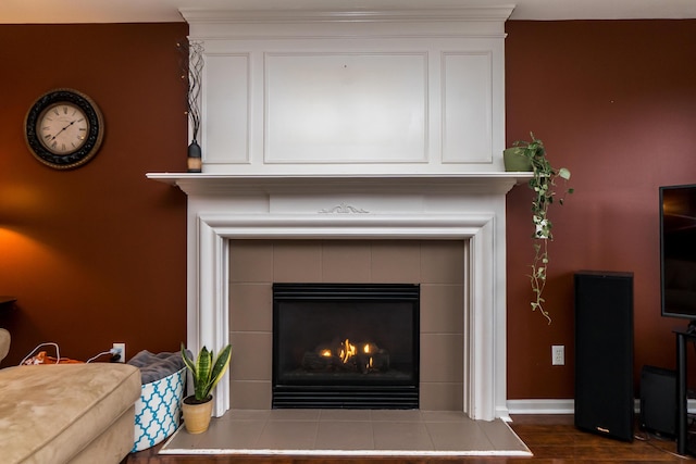 room details featuring baseboards, wood finished floors, and a tile fireplace