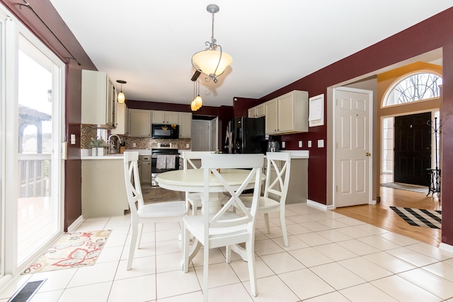 dining room featuring light tile patterned floors, plenty of natural light, visible vents, and baseboards